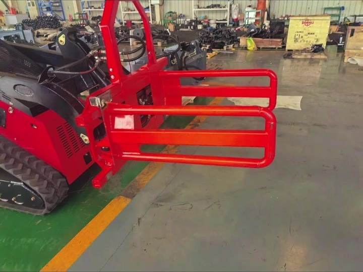 Skid steer bale grapple attachment mounted on a compact loader